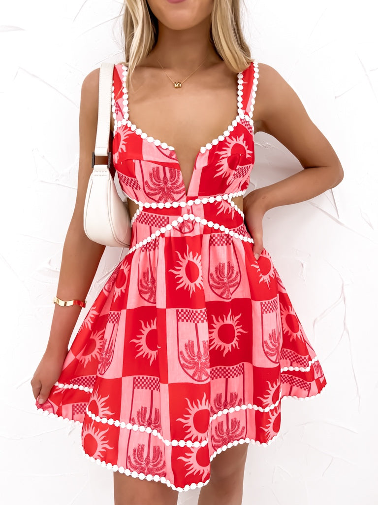 Red and white patterned dress worn by a model on a white background